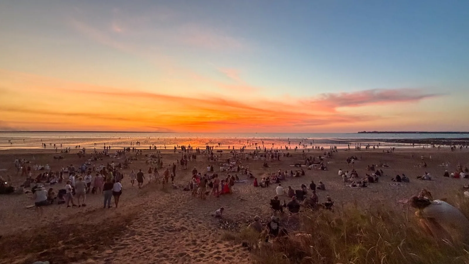 Crowds watching a vivid sunset over the Arafura Sea at Mindil Beach, Darwin.