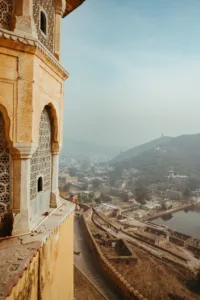 An ochre tower of Amber Fort overlooking its ramparts, Maota Lake and the hazy Jaipur hills.