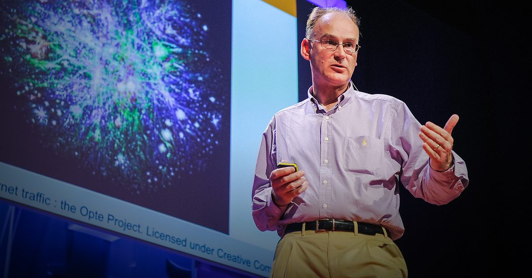 Matt Ridley on a TED stage, a projected network image behind him
